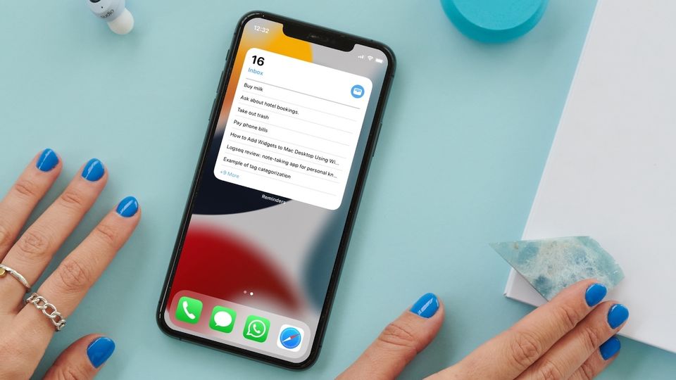 iPhone on blue table with hands on both sides showing reminders widget