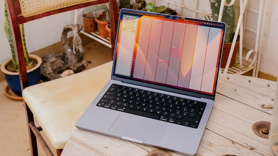 MacBook Pro on wooden table with a chair on the side showing calendar added to Mac Desktop