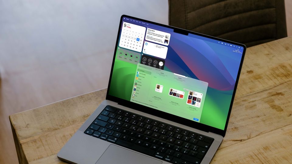 MacBook Pro on wooden table showing desktop widgets