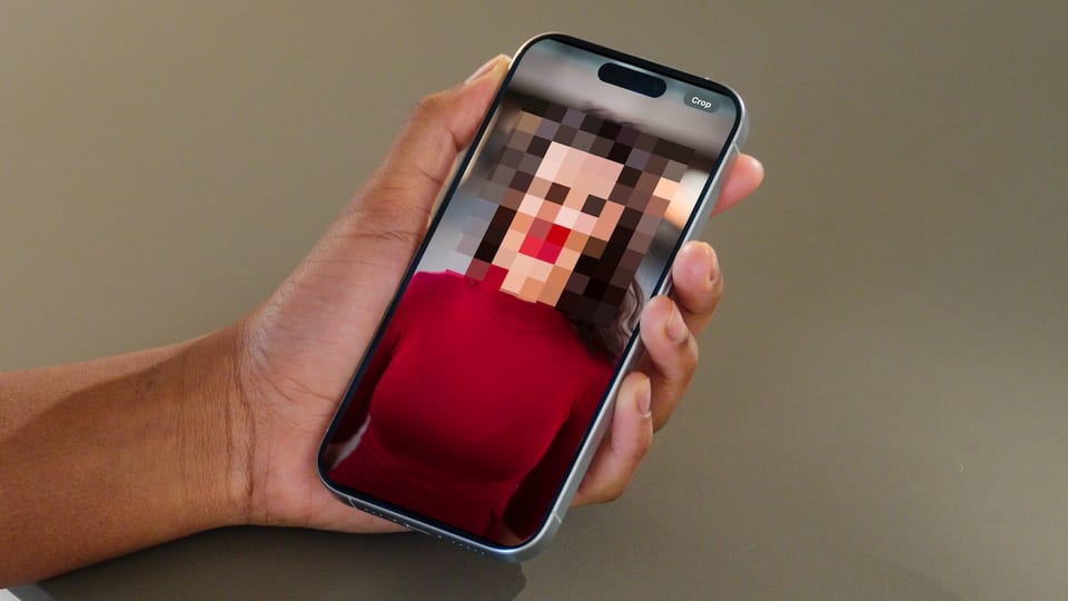 iPhone in hand showing photo with pixelated face